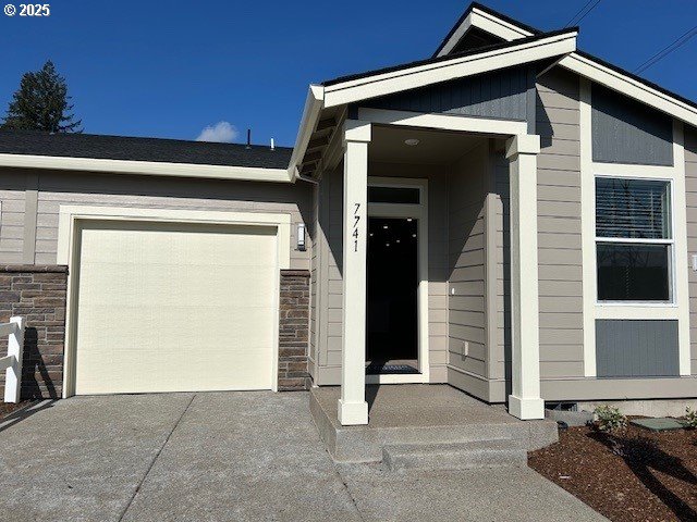 view of exterior entry featuring driveway, stone siding, and an attached garage