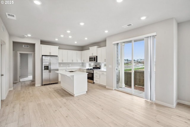 kitchen with a sink, stainless steel appliances, light wood-type flooring, and visible vents