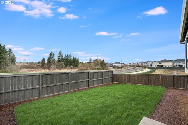 view of yard featuring a fenced backyard and a residential view