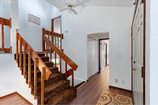 stairs featuring hardwood / wood-style flooring, a towering ceiling, and ceiling fan