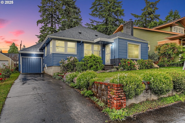 view of front facade with a chimney, asphalt driveway, a shingled roof, and a garage