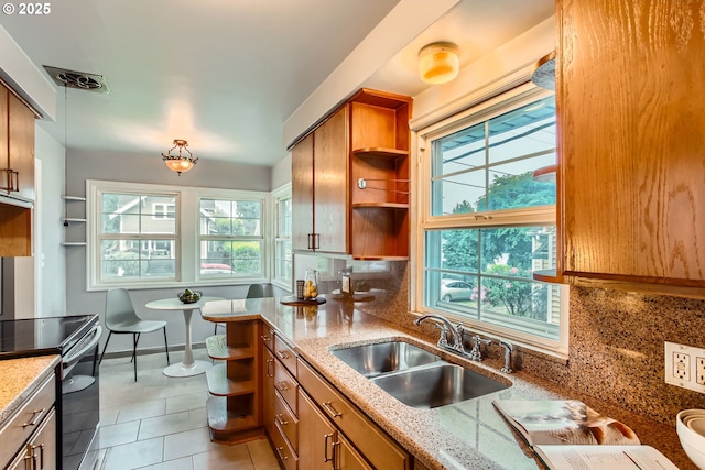 kitchen featuring open shelves, a sink, stainless steel range with electric stovetop, brown cabinets, and light tile patterned floors