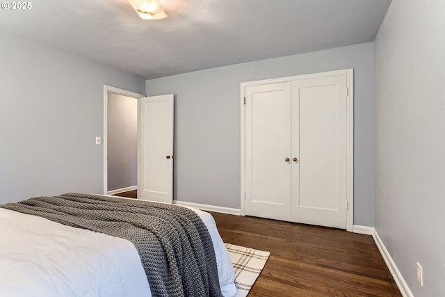 bedroom featuring dark wood-type flooring, baseboards, and a closet