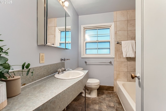 full bathroom with a sink, stone finish flooring, healthy amount of natural light, and toilet