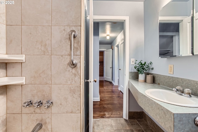 bathroom with a sink, a shower, and baseboards