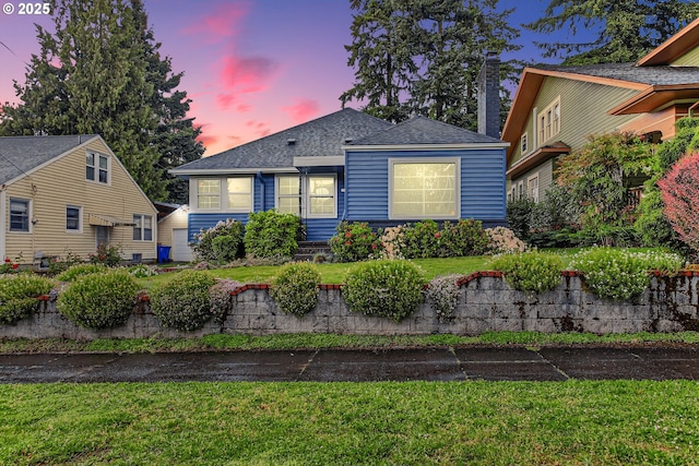 view of front of house featuring a front lawn, a shingled roof, and a chimney