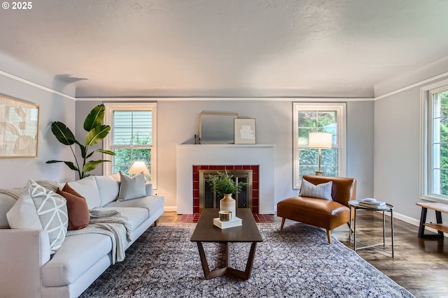 living area featuring a tile fireplace, wood finished floors, and baseboards