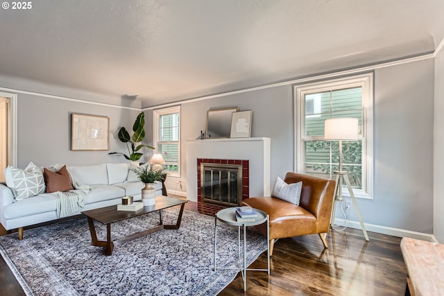living area featuring wood finished floors, baseboards, a fireplace, and crown molding