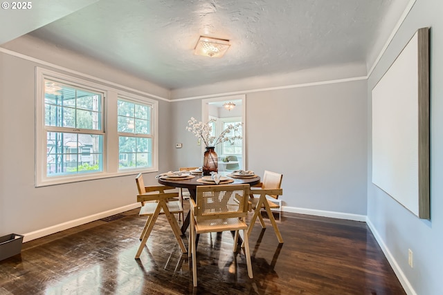 dining space with baseboards, dark wood finished floors, a textured ceiling, and ornamental molding