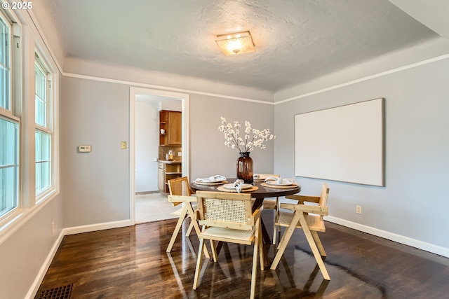 dining area featuring baseboards, dark wood-style flooring, and a textured ceiling