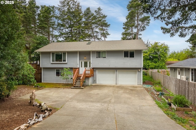 raised ranch featuring fence, a garage, and concrete driveway