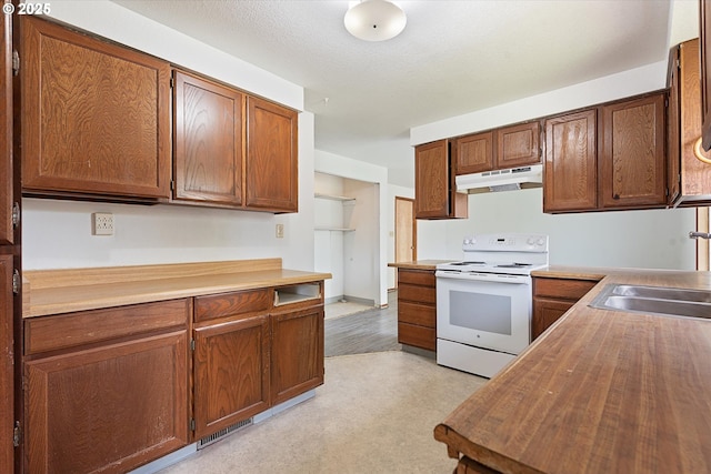 2509 E J Ct, La Grande, OR 97850 - kitchen with white electric stove, a sink, butcher block counters, light floors, and under cabinet range hood
