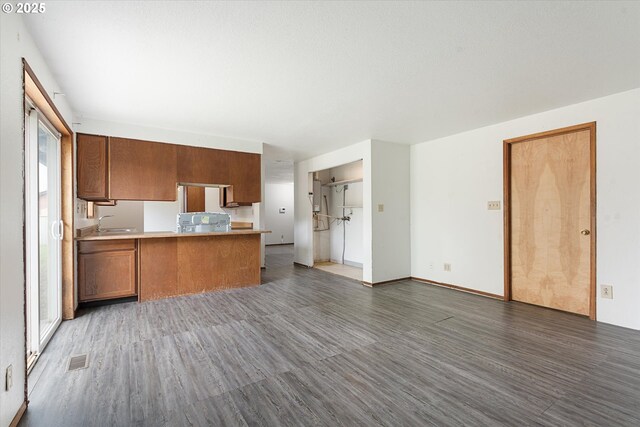 2509 E J Ct, La Grande, OR 97850 - kitchen with visible vents, a peninsula, open floor plan, light wood-type flooring, and brown cabinets