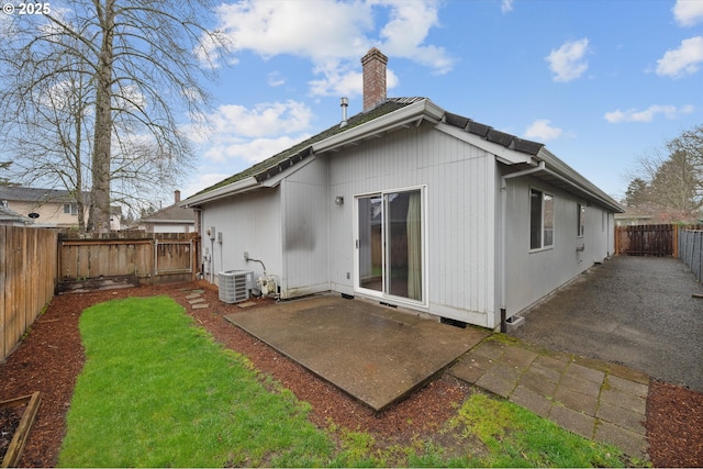 back of house featuring a fenced backyard, a yard, a chimney, and a patio