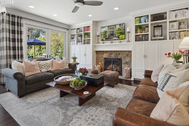 living area with a fireplace, wood finished floors, built in features, and ceiling fan