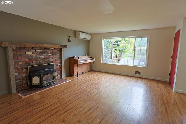 650 S Cammann St, Coos Bay, OR 97420 - unfurnished living room featuring a wood stove, wood finished floors, and a wall mounted air conditioner