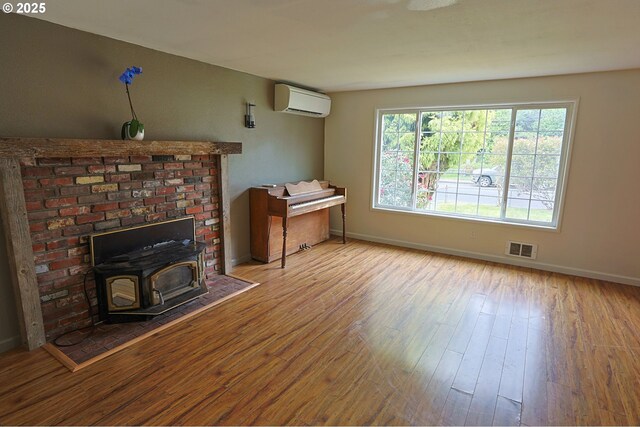 650 S Cammann St, Coos Bay, OR 97420 - living area featuring an AC wall unit, wood finished floors, and a wood stove