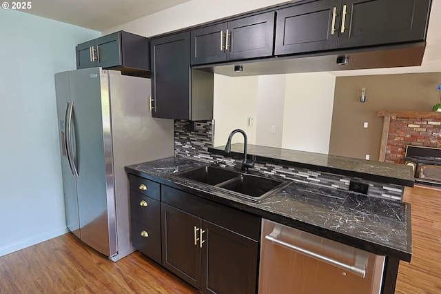 650 S Cammann St, Coos Bay, OR 97420 - kitchen with appliances with stainless steel finishes, dark countertops, light wood-style flooring, a peninsula, and decorative backsplash