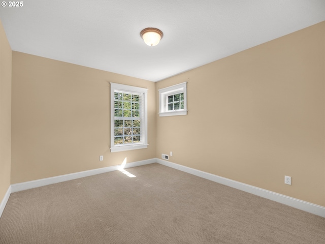 spare room with baseboards and light carpet