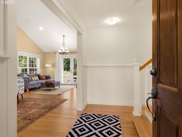 entrance foyer featuring an inviting chandelier, baseboards, a wainscoted wall, and light wood-style flooring