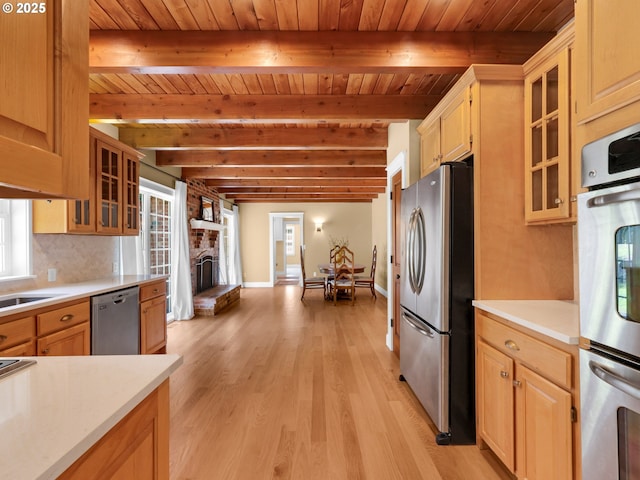 kitchen with appliances with stainless steel finishes, light wood finished floors, a fireplace, light countertops, and wooden ceiling