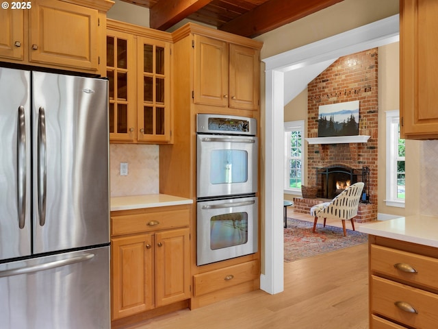 kitchen with light countertops, appliances with stainless steel finishes, plenty of natural light, and a fireplace