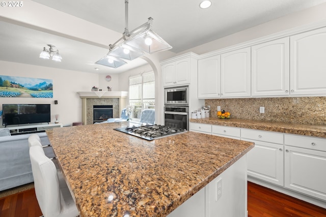 12696 NW Alsace Ln, Portland, OR 97229 - kitchen featuring stainless steel appliances, open floor plan, a kitchen island, dark wood-style floors, and white cabinets