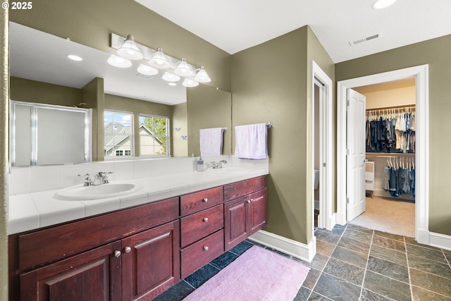 12696 NW Alsace Ln, Portland, OR 97229 - full bath with double vanity, a stall shower, stone finish flooring, baseboards, and a walk in closet