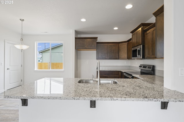 469 N 35th, Springfield, OR 97478 - kitchen with appliances with stainless steel finishes, a sink, dark brown cabinets, light stone counters, and a peninsula