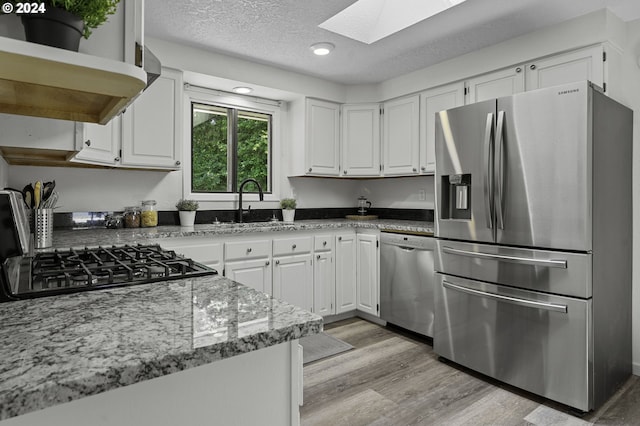 5323 Verda Ln, Keizer, OR 97303 - kitchen with stainless steel appliances, a skylight, open shelves, under cabinet range hood, and white cabinetry