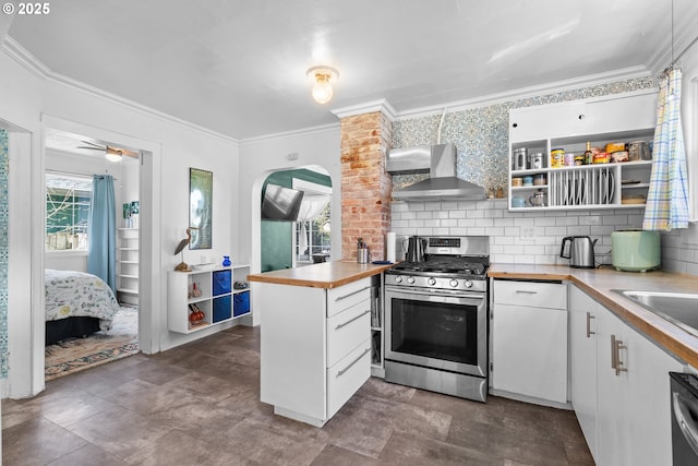 kitchen featuring stainless steel range with gas cooktop, open shelves, tasteful backsplash, white cabinetry, and wall chimney range hood