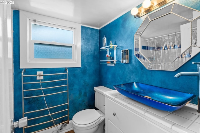 bathroom with a textured wall, vanity, and toilet