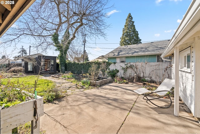 view of patio featuring an outbuilding, fence, and a garden