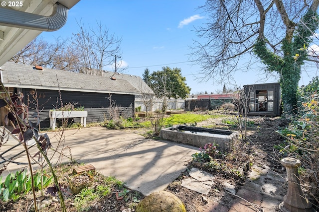 view of patio / terrace featuring an outdoor structure, fence, and a garden