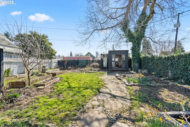 view of yard with a fenced backyard, a vegetable garden, and an outdoor structure