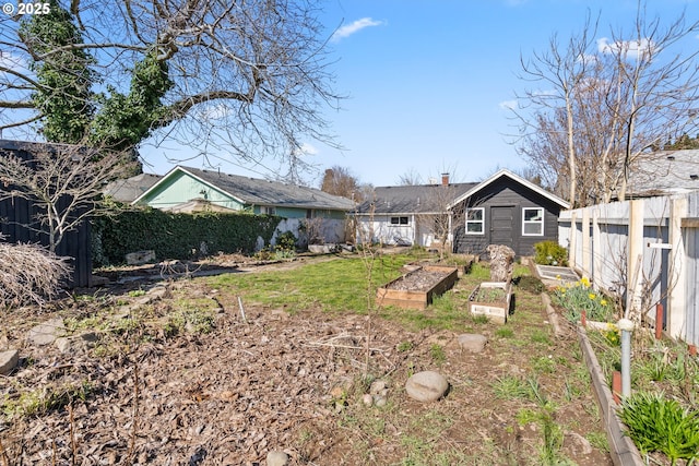 rear view of property featuring a chimney, a vegetable garden, and fence