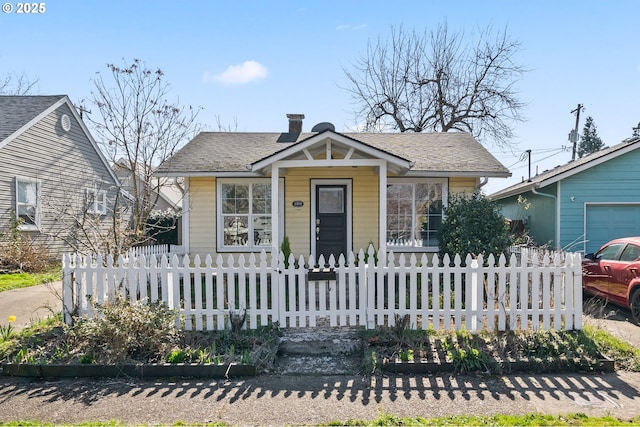 bungalow-style house with a fenced front yard and roof with shingles