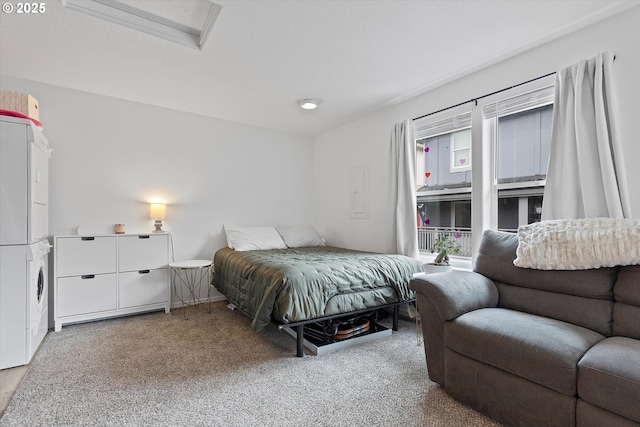 carpeted bedroom with stacked washer / drying machine and attic access