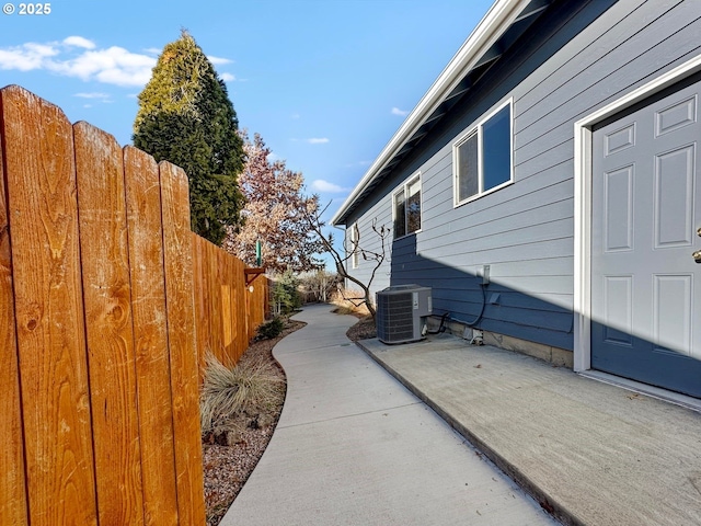 view of side of property featuring cooling unit, a patio area, and fence