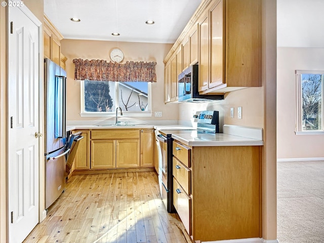 kitchen featuring a sink, light countertops, light brown cabinetry, stainless steel appliances, and light wood-style flooring