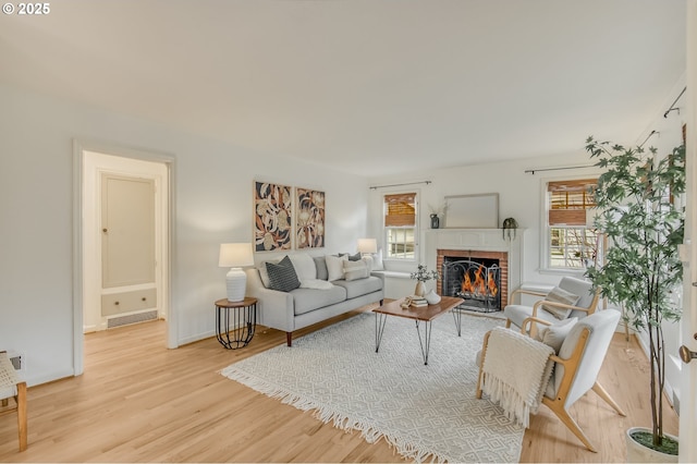 living area with visible vents, a fireplace, a wealth of natural light, and light wood-style floors