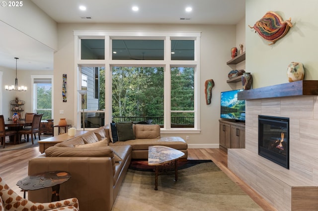 living room with light wood-type flooring, an inviting chandelier, and a fireplace