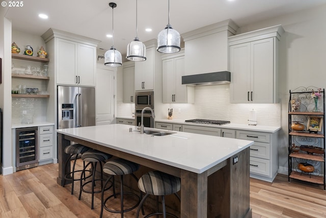 kitchen with appliances with stainless steel finishes, sink, beverage cooler, hanging light fixtures, and custom range hood