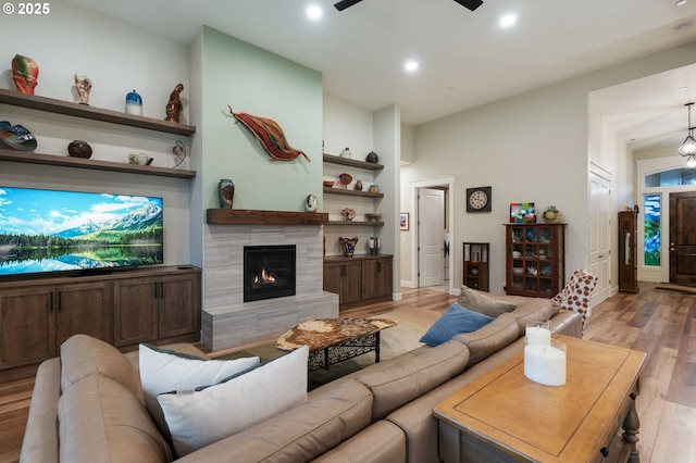 living room featuring a fireplace, light hardwood / wood-style floors, and ceiling fan