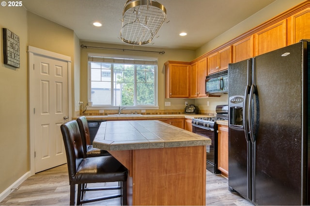9575 SW Tephra Ter, Beaverton, OR 97007 - kitchen featuring black appliances, a sink, a kitchen island, light wood-style flooring, and recessed lighting