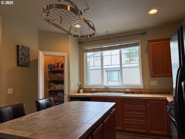 9575 SW Tephra Ter, Beaverton, OR 97007 - kitchen with tile countertops, a sink, recessed lighting, freestanding refrigerator, and a center island