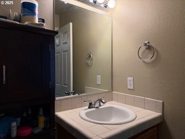 bathroom with a textured wall and vanity