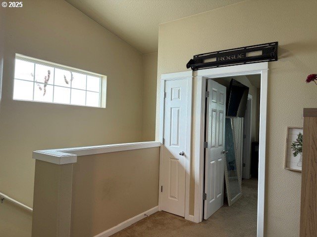 hallway featuring carpet and baseboards