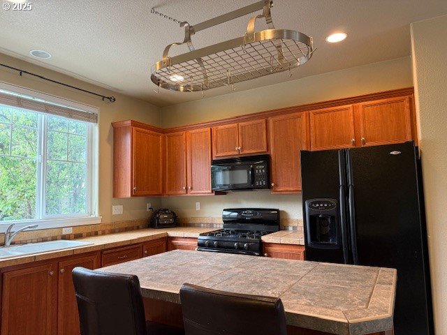 9575 SW Tephra Ter, Beaverton, OR 97007 - kitchen with black appliances, a sink, brown cabinetry, a kitchen island, and recessed lighting