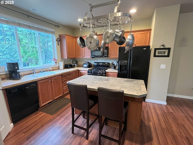 kitchen featuring black appliances, dark wood-style floors, a sink, a center island, and recessed lighting